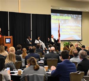 All three local school superintendents speaking on stage before audience 